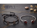 ooma brand display banner showing 2-piece ankle stack with black macrame butterfly cord and teardrop garnet bypass cuff flat lay on dark stone