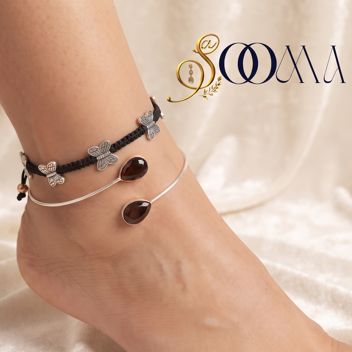 Close-up view of model foot adorned with a bohemian black butterfly cord anklet and teardrop carnelian silver bypass cuff on white velvet