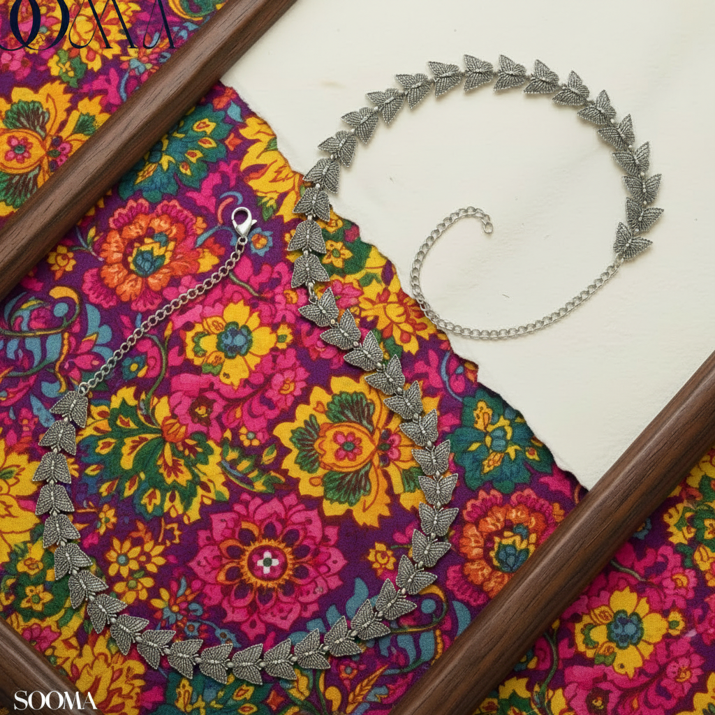 Sooma brand oxidized silver butterfly link waist chain displayed flat on blue satin fabric inside wooden frame