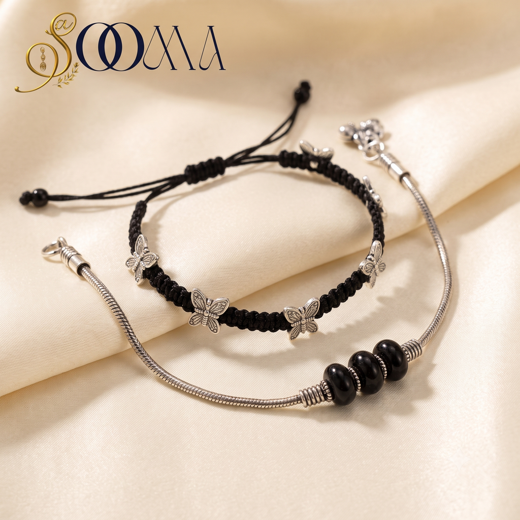Sooma brand handcrafted 2-piece layered anklet stack featuring black macrame cord with silver butterflies and silver snake chain with black onyx beads on cream fabric