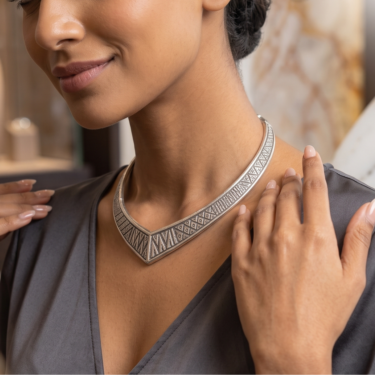 Front view close-up of model wearing etched tribal geometric V-dip silver Hasli collar