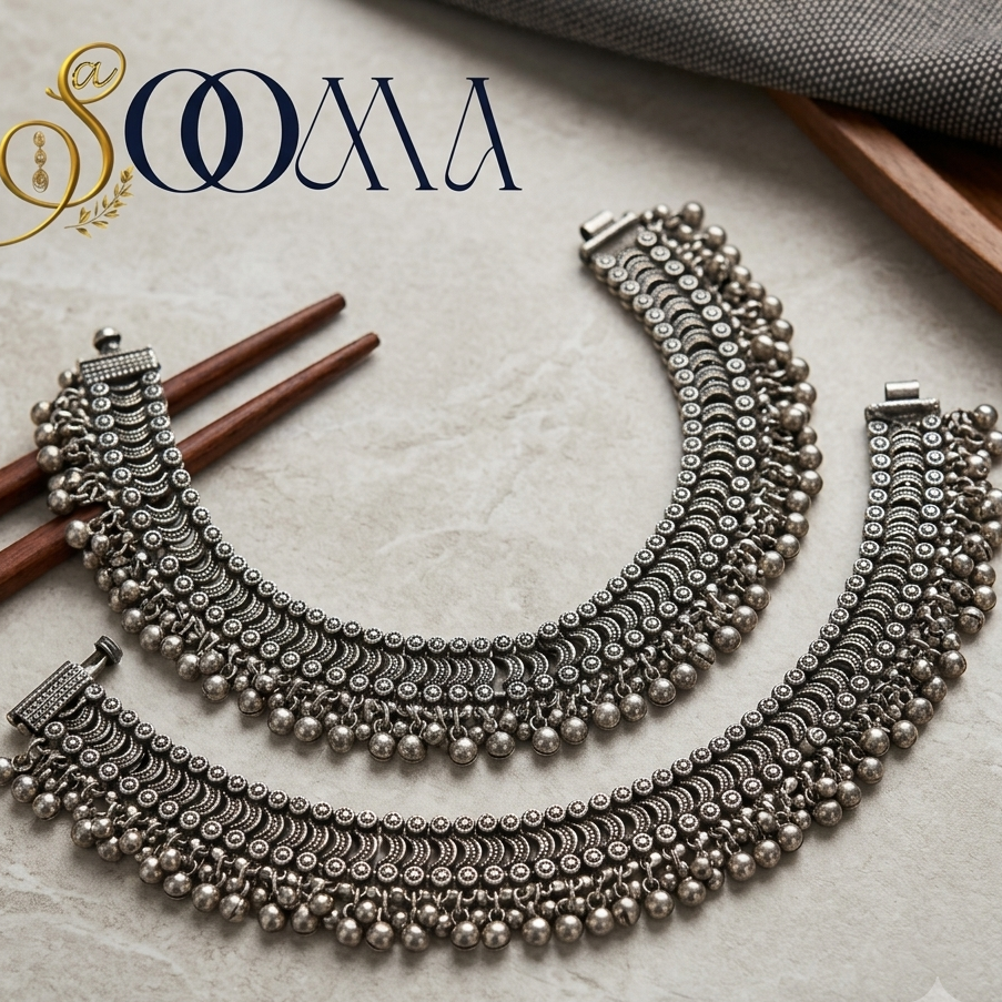 Flat lay shot of Sooma broad oxidized silver tribal payal anklets pair with ghungroo fringe on marble surface