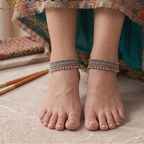 Front view of model wearing broad handcrafted oxidized silver tribal anklets pair paired with colorful ethnic skirt