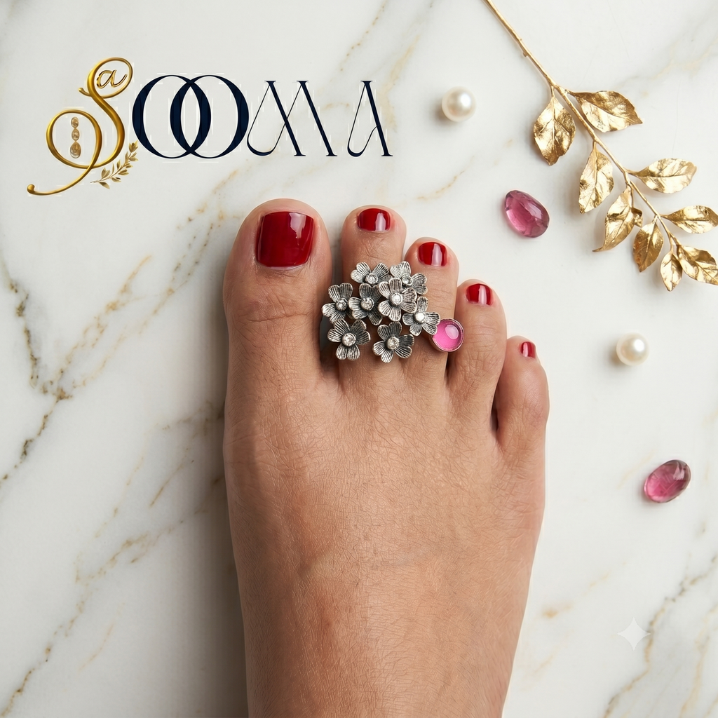 "Top down view of handcrafted silver floral bichhiya with pink gemstone accent on an Indian foot"