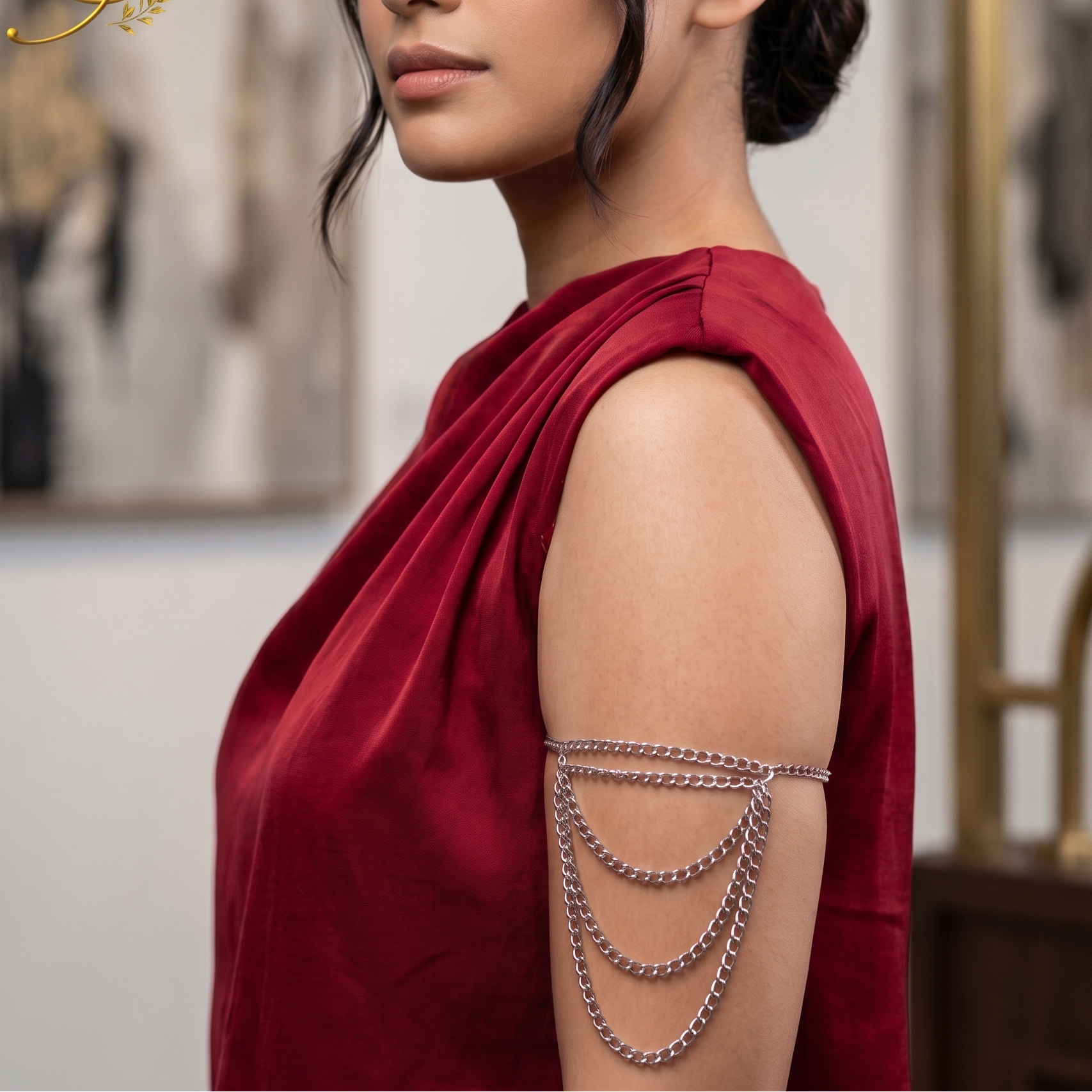 A woman in a draped red top wearing a rose chain armband, shown in profile against an elegant indoor background with a gold-framed mirror.