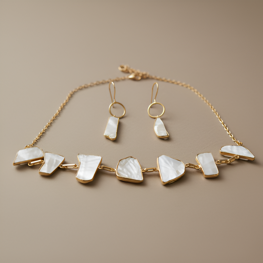 Gold necklace and earrings with white stones on a beige background