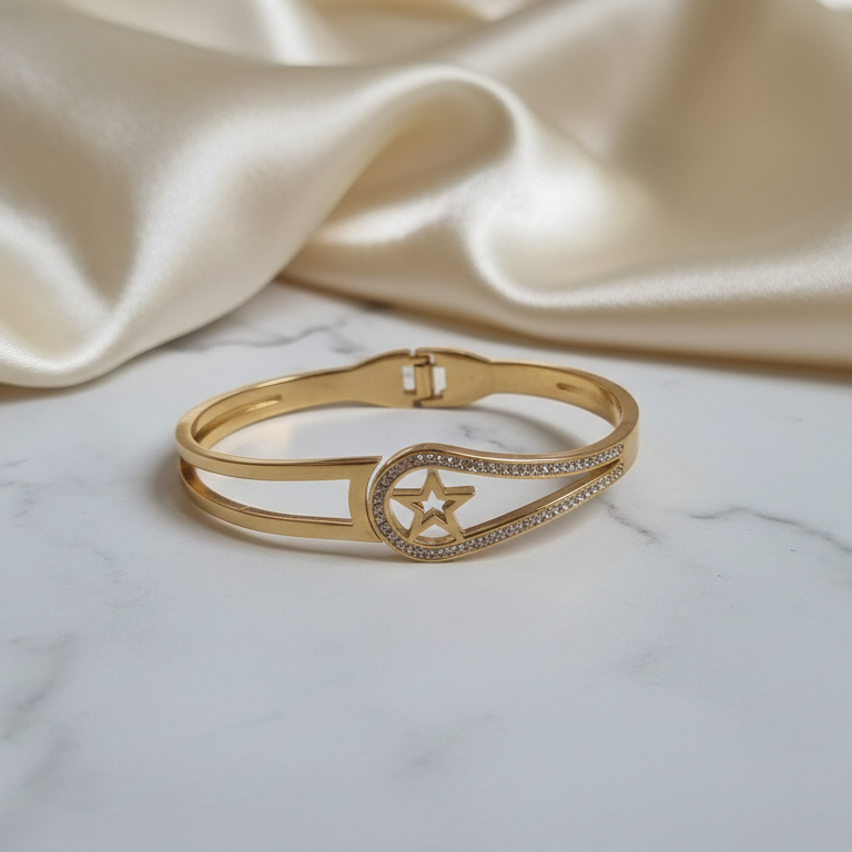 Gold bracelet with star and moon design on a marble surface with beige fabric