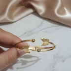 Gold bracelet held by a hand showing the way it opens