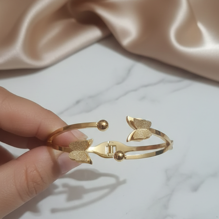Gold bracelet held by a hand showing the way it opens