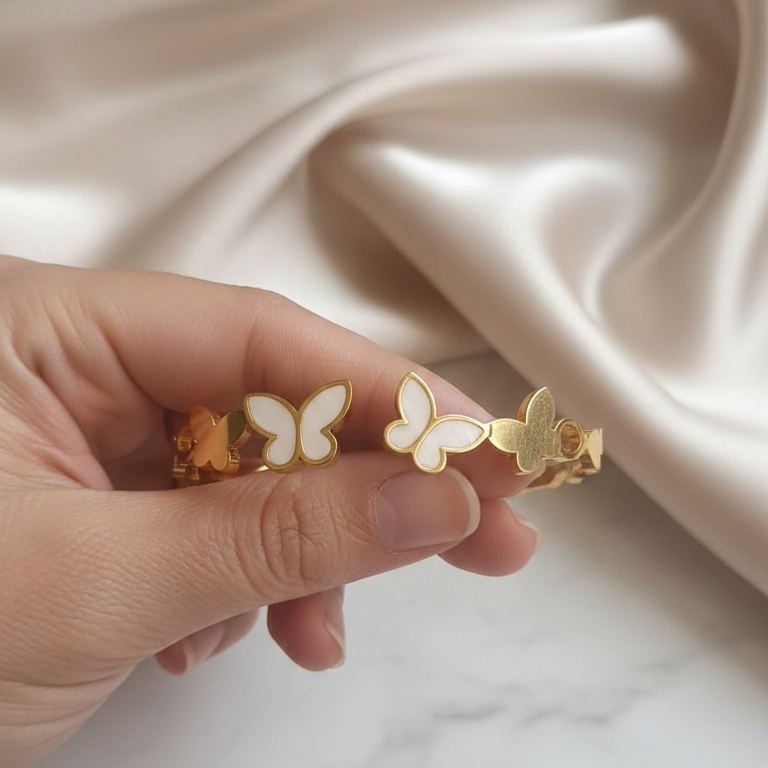 Hand holding opening a gold plated butterfly bracelet on a wrist