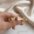 Hand holding opening a gold plated butterfly bracelet on a wrist