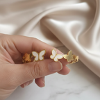 Hand holding opening a gold plated butterfly bracelet on a wrist