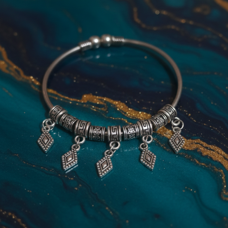 Silver bracelet with dangling charms on a textured blue surface