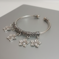Oxidised Silver Bangle with floral charms on a gray surface