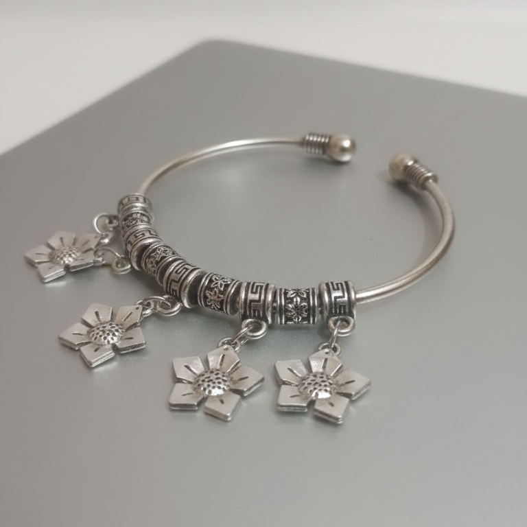 Oxidised Silver Bangle with floral charms on a gray surface