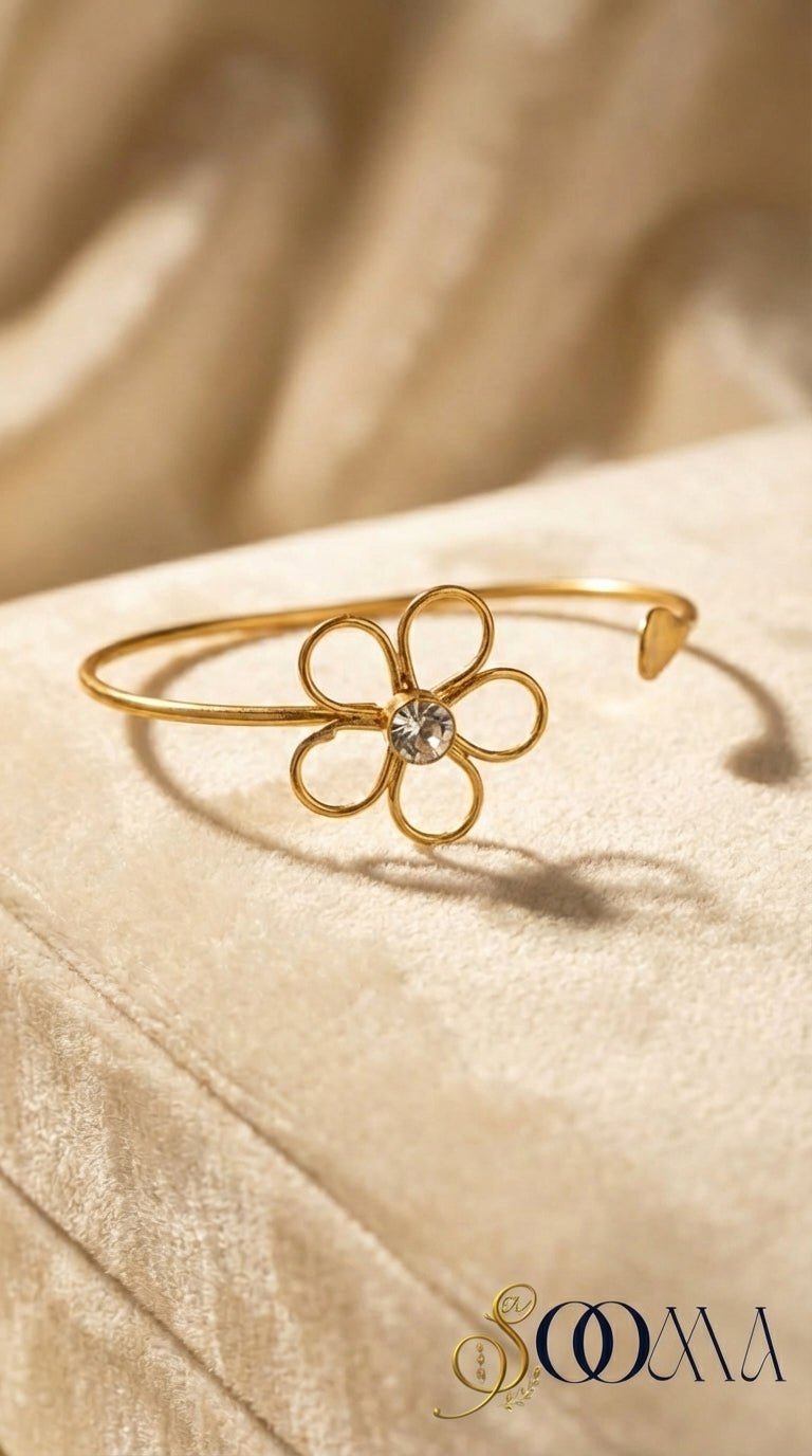 Gold flower-shaped ankle bracelet on a beige fabric background