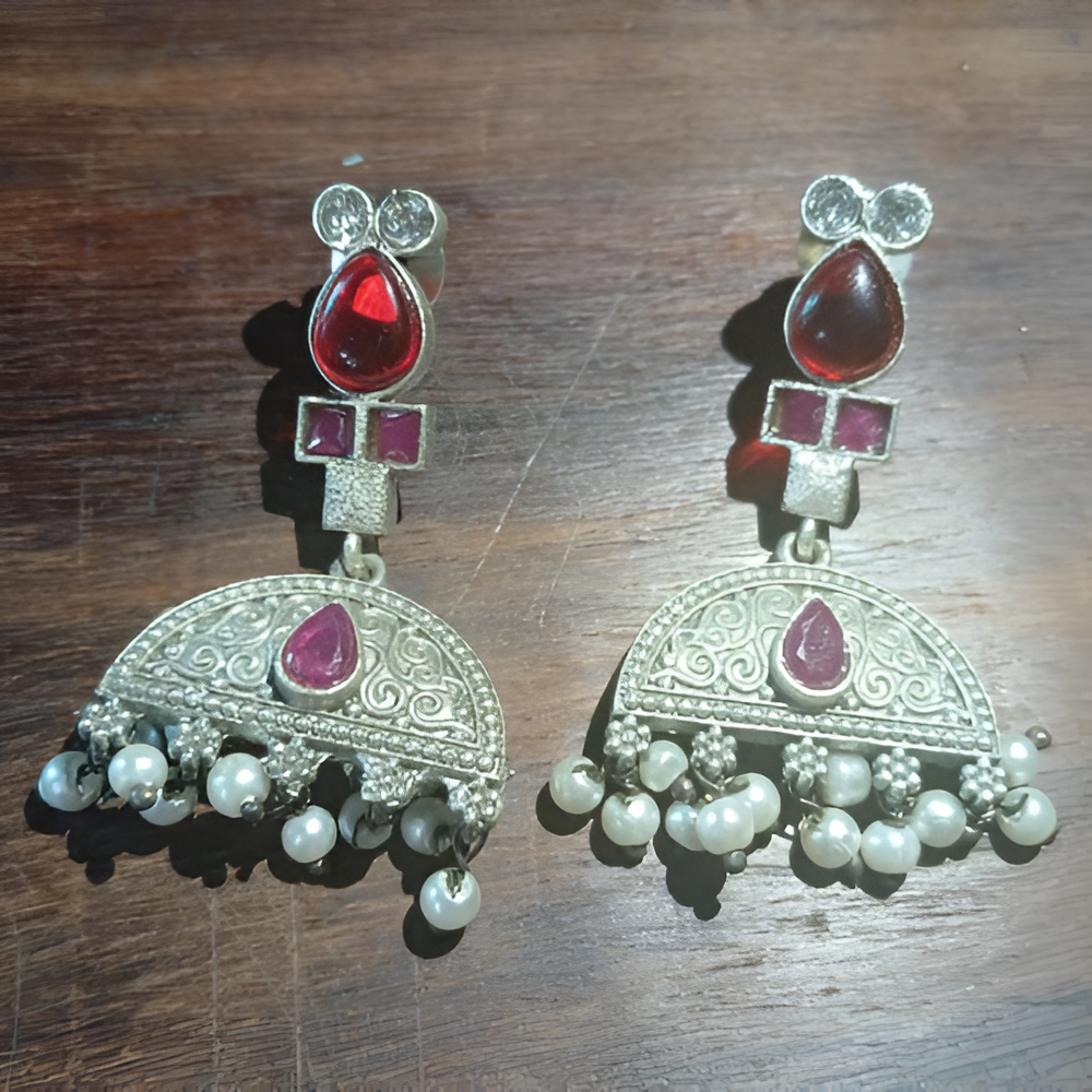 Pair of classic indian earrings with red and pink gemstones on a wooden surface
