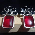 Pair of silver oxidised earrings with red and black stones .