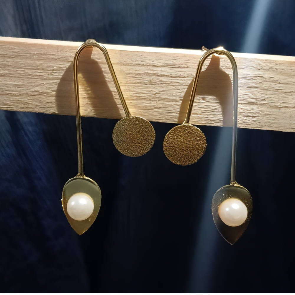 Unique Gold earrings with pearl drops on a wooden stand 