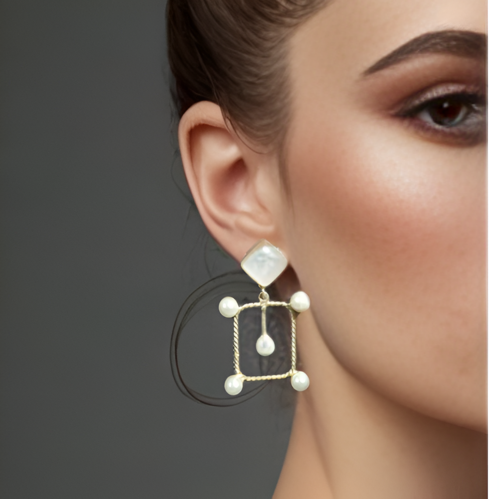 Picture of a model wearing a gold earring with a central dark white and smaller pearls.