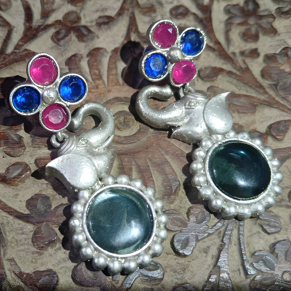 Pair of oxidised silver elephant earrings with stone details .