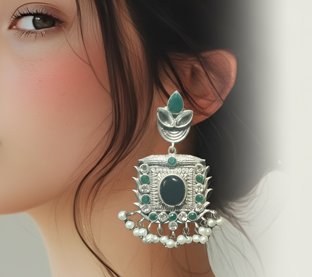 A woman wearing silver oxidised traditional earrings with black & green stones